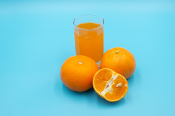 Orange juice in glass with fresh orange fruit on blue color background.