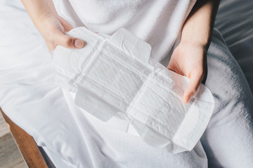 Closeup of woman hands holding sanitary napkins or menstruation pad before wearing it. Women using it during menstruation to avoid damage to clothing. © boyloso