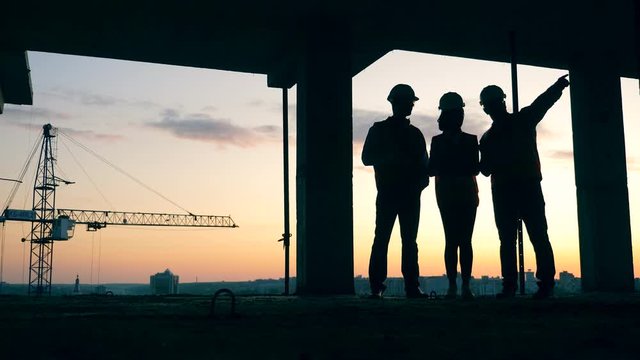 Workers stand on a building site, talking. Construction workers at modern construction site.