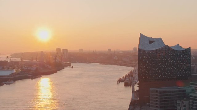 4K Aerial Elbe river in Hamburg during sunrise, Elbphilharmonie concert hall modern building and sailing ships