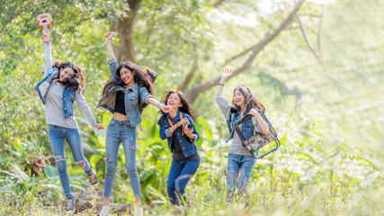 Fototapeta premium Group of Asian female having fun hiking outdoor in deep forest holiday.