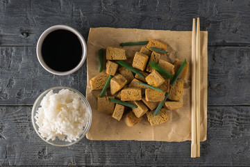 Fototapeta premium Rice, soy sauce, chopsticks and grilled tofu cheese on a wooden table. Flat lay.