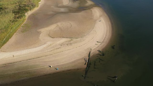 aerial drone camera orbit right over Shell Bank Creek in Brooklyn, with the creek shore & water in view with fisherman & his kid