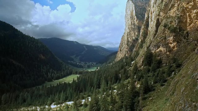 Green valley floor, dark green spruce trees, a spec of blue sky and impressive rock walls. Aerial of Vallunga / Langental.
