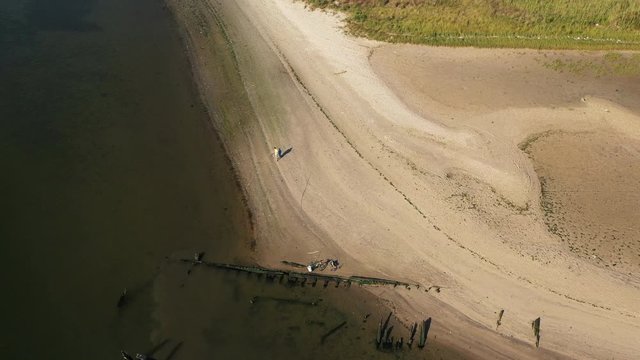 aerial drone camera pan forward tilt down over Shell Bank Creek in Brooklyn, with the creek shore & water in view with fisherman & his kid