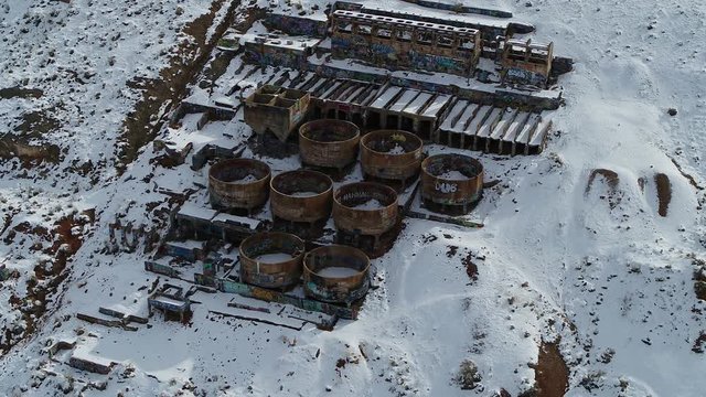 A drone orbits the rusty Old Tintic Mill in Geneloa, Utah, revealing the decaying water tanks, leaching tanks, roasters and crusher built into the mountain in 1920.