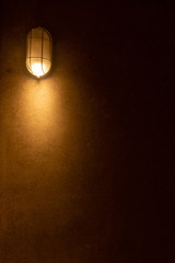 warm light bulb at wall in dark room. vertical picture .