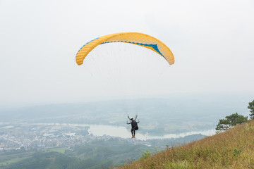 Yellow paraglider just taking off at the top of the mountain