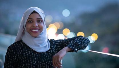 African  modern Muslim woman in night at balcony