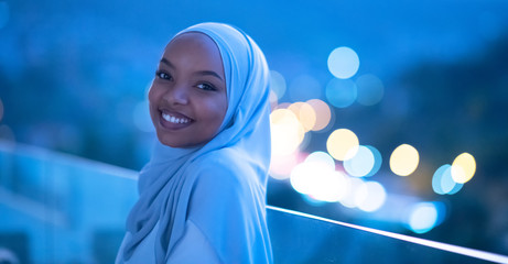 African  modern Muslim woman in night at balcony