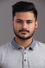 Face of young handsome Indian man looking at camera
