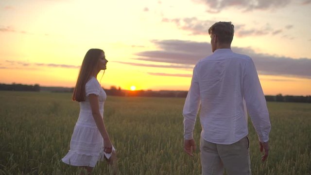 happy couple outdoors having fun, walking on wheat field at sunset nature. romantic happy family in Love. Young man woman holding hands. Freedom Happiness Travel Summertime, Sun lens flare slow motion
