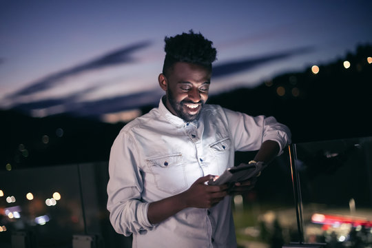 Young  Afro Man On  Street At Night Using Phone