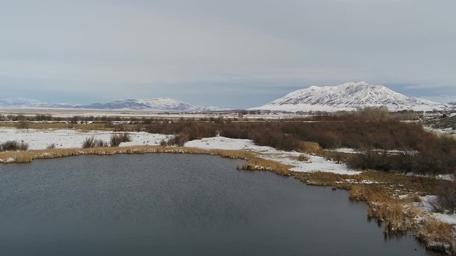 An aerial drone shot flying over the catch pond and desert in the winter, near Genola, Utah and the Old Tintic Mill.