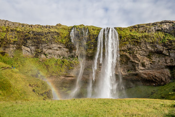 Seljalandsfoss waterfall drops from cliffs that allow people to walk behind the falls in Southern Iceland