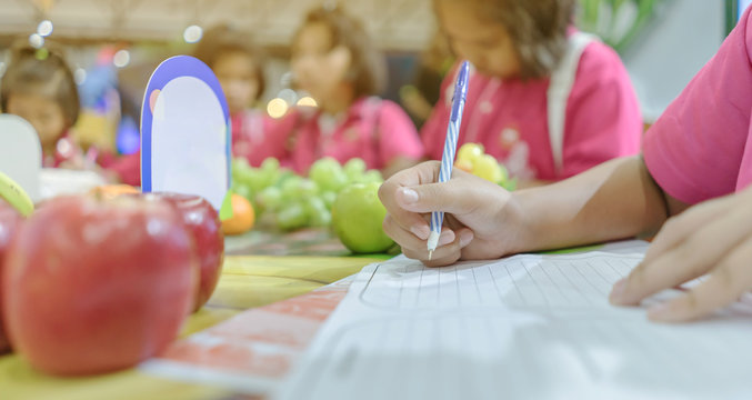 Primary school girls learn and take notes about different types of fruits at school.