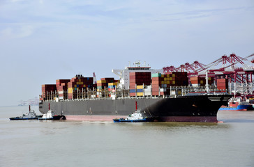 Large cargo container ship arriving to the port of Yangshan, tug boats assisting with maneuvering...