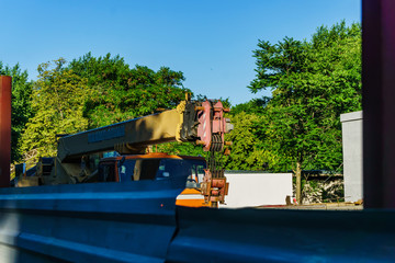 The mobile crane in the non-working condition is standing on the construction site in anticipation of cargo for lifting