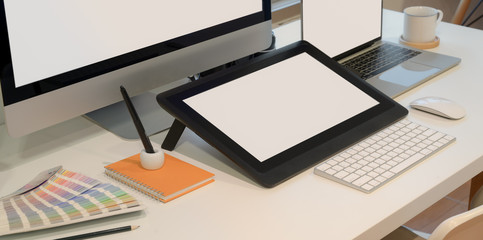 Close-up view of designer workplace with blank screen digital tablet with desktop computer