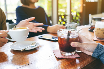 Closeup image of people enjoyed talking and drinking coffee together in cafe