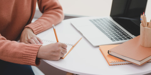 Young woman working on her project while drafting her idea on notebook
