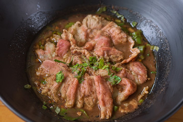 White noodle soup with meatball and beef stewed served in a black bowl. In Thailand, we call this food 