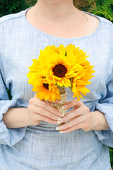 The woman is holding a bouquet of sunflowers.