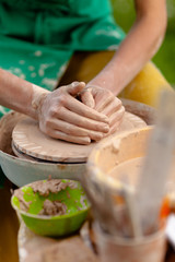 Hand craft making pottery on wheel. Female hands mold ceramic plate from clay (pot).