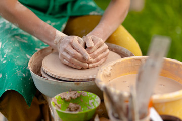 Hand craft making pottery on wheel. Female hands mold ceramic plate from clay (pot).