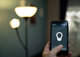 Smart home: man controlling lights with app on his phone.