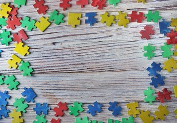 colorful puzzles on a white wooden background, frame, concept of early childhood autism