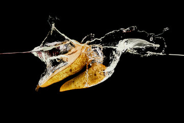 pear halves falling deep in water with splash isolated on black