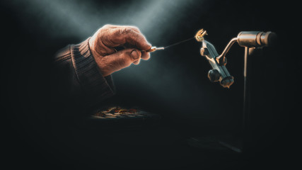 Close up of fisherman tying a fly for fishing .