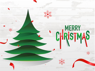 Red and green text Merry Christmas and paper cut xmas tree on white wooden background for celebration concept.