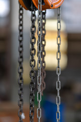 Orange steel load-lifting hook. Black steel chain.