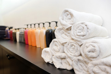 Rolled up white towels with cosmetic bottles. Soap and shampoo bottles and white towels rolled on a...