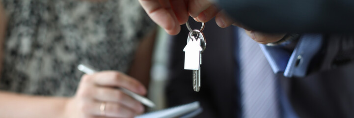 Focus on male hands holding keys to housing. Couple of married signing good deal of property purchase. Meeting and negotiations concept. Blurred background