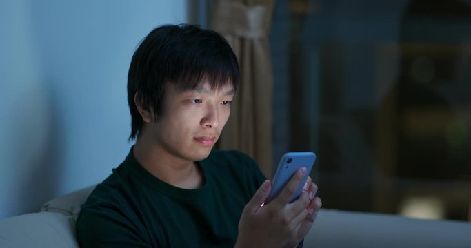 Man use of mobile phone and sit on sofa at night