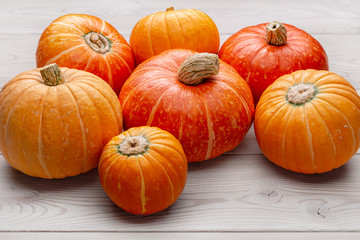 Set of ripe round yellow and orange pumpkins on a light wooden surface. Studio shot.