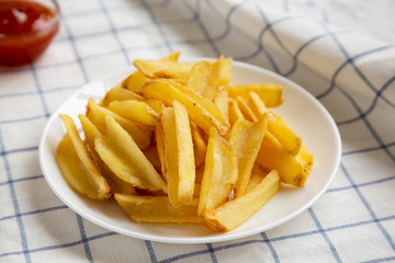 Homemade french fries with sour-sweet sauce on a white plate, low angle view. Closeup.