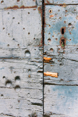 Une vieille serrure rouillée sur une porte en bois bleue.