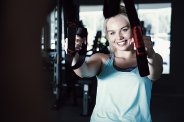 Fototapeta na wymiar Sporty woman doing TRX exercises in the gym