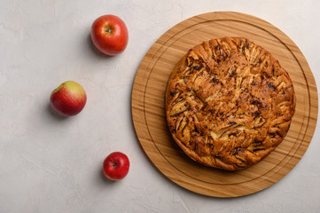 Cornish apple pie top view on rustic style white background. Next to three apples. Copy space for...