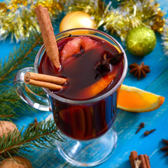 Christmas mulled red wine with spices and fruits on a blue wooden rustic table. Traditional hot drink with cinnamon, cardamom, oranges  and anise at Christmas time.