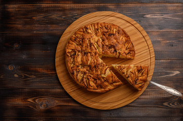 Cornish apple pie with a cut piece on the shoulder blade top view on rustic style brown background. Copy space for your text