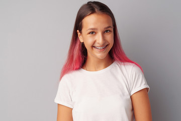 Young girl teenager with pink hair happy and smiling over gray background