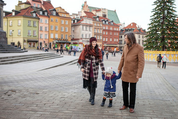 Fototapeta premium Happy Family - mother, father and little girl walking in autumn city and having fun