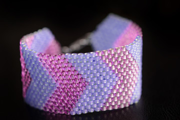 Beaded bracelet from beads of two colors on a dark background close-up