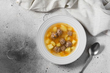 A bowl of meatball soup on the gray kitchen table