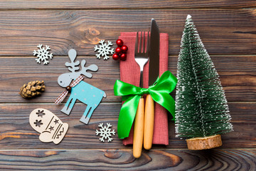 Top view of fork and knife tied up with ribbon on napkin on wooden background. Close up of christmas decorations and New Year tree. Happy holiday concept